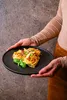 A person holding a plate of pasta. Náhľad obrázku produktu