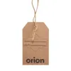 A brown cardboard tag with twine attached, hanging against a white background. The tag has printed text and a decorative border. Produktbild-Vorschau