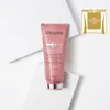 A pink tube of Kerastase hair conditioner is placed on a white surface with geometric folds. Podgląd zdjęcia produktu