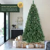 A decorated Christmas tree stands in a modern living room, surrounded by wrapped gifts. Produktbild-Vorschau