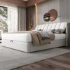 A modern bedroom with a white upholstered bed as the focal point, featuring LED lighting and decorative wall art. Produktbild-Vorschau