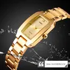 A close-up of a gold-colored watch with water splashes around it. Produktbild-Vorschau