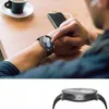 A person is using a smartwatch while sitting at a table with a coffee cup and a phone. Voir les images du produit