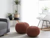 A cozy living room scene with a gray sofa, two knitted poufs, a side table with plants, and a rocking chair. Produktbild-Vorschau