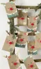 A collection of handmade reindeer-themed advent calendar bags hanging on a wooden ladder with pine branches. Produktbild-Vorschau