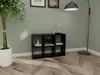 A black cube bookshelf is placed on a wooden floor next to a tall potted plant and a floor lamp. Produktbild-Vorschau