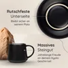 A black mug with steam rising from it sits next to a rock formation, with a black plate in the background. Text overlays describe product features. Voir les images du produit