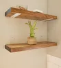 Two wooden shelves mounted on a light-colored wall, with a plant on the lower shelf. Produktbild-Vorschau