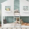 A white bunk bed shaped like a house with windows and a ladder, decorated with stuffed animals and books. Produktbild-Vorschau