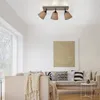 A modern living room with a sectional sofa, decorative pillows, a throw blanket, and a large piece of abstract art on the wall. A ceiling light fixture with three adjustable spotlights is visible. Produktbild-Vorschau