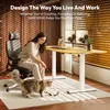 A woman is playing with her cat next to a standing desk in a home office setting. Produktbild-Vorschau