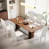 A dining room scene with a wooden table and six white chairs. Náhled obrázku produktu