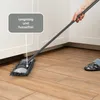 A person is using a mop to clean a wooden floor in a kitchen or utility room. Produktbild-Vorschau