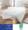 A white duvet and pillow set laid out on a wooden bed frame in a bedroom. Produktbild-Vorschau