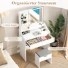 A white vanity table with a mirror and stool, set up in a bedroom next to a bed and a plant. Anteprima dell’immagine prodotto
