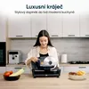 A woman is using a food slicer in a modern kitchen. Náhled obrázku produktu