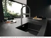 A modern kitchen sink with a faucet, set against a dark countertop and wall, with a large window showing greenery outside. Anteprima dell’immagine prodotto