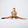 A man is performing a split on a white background, with kinesiology tape applied to his body. Náhľad obrázku produktu
