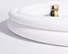 A coiled white hose with a brass and black fitting on a white background. Produktbild-Vorschau