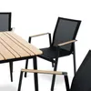 A close-up view of a modern outdoor dining set, featuring a slatted wooden tabletop and black metal chairs with mesh seating and wooden armrests, set against a clean white background. Produktbild-Vorschau