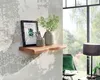 A wooden shelf with decorative items on a textured wall, next to a window with greenery outside. Náhled obrázku produktu