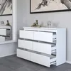 A modern white dresser with six drawers is shown in a room with textured wallpaper and a large mirror reflecting another dresser. Produktbild-Vorschau