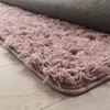 A close-up view of a fluffy pink rug with a gray backing, lying on a light wood floor. Produktbild-Vorschau
