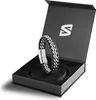 A black and silver leather bracelet with a metal clasp is displayed inside an open black gift box. Anteprima dell’immagine prodotto