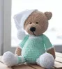 A crocheted teddy bear wearing pajamas and a nightcap, sitting on a wooden surface. Náhľad obrázku produktu