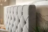 A close-up view of a tufted headboard of a bed, with a marble-patterned wall and a plant in the background. Náhled obrázku produktu