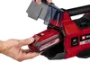 A person is inserting a red battery into a red power tool, with a transparent cover partially open. Produktbild-Vorschau