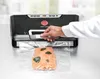 A person is using a vacuum sealer to seal a piece of salmon in a plastic bag. Podgląd zdjęcia produktu