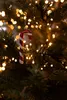 A close-up of a candy cane ornament hanging on a Christmas tree, surrounded by fairy lights. Produktbild-Vorschau
