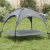 A gray dog bed with a canopy is set up on a grassy lawn in front of a wooden fence and some bushes. Anteprima dell’immagine prodotto