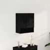 A black wall-mounted cabinet with two doors and a shelf below, shown on a white wall above a dark wooden dresser. Voir les images du produit