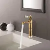 A vintage-style brass faucet with water running into a white sink, flanked by two spherical candles. Náhled obrázku produktu