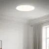 A white LED ceiling light is mounted on a white ceiling in a room with white walls and decorative molding. A light gray curtain is visible on the right side of the image. Náhľad obrázku produktu