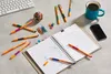 A desk with office supplies including pens, a notebook, a coffee mug, and a smartphone. Produktbild-Vorschau