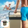 A man carries a cooler on a beach with a woman relaxing in a chair in the background. Anteprima dell’immagine prodotto
