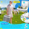 A man is carrying a cooler box in a grassy outdoor setting with a lake and trees in the background. Two children are playing nearby. The cooler box is open, showing fruit and a bottle of beer. There are also images of bottles and ice cubes. Produktbild-Vorschau