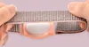 Hands stretching a pink fabric band with a pink plastic holder for an Apple AirTag. Náhled obrázku produktu