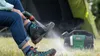A person is cleaning hiking boots with a portable cleaning device outdoors, with a tent and a power station in the background. Anteprima dell’immagine prodotto