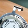 A close-up of a stainless steel oven thermometer, showing the dial and a hook. Produktbild-Vorschau