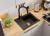 A modern kitchen sink area with a black granite sink, faucet, and a small potted plant on a wooden countertop. Produktbild-Vorschau