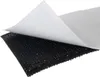 A close-up of a black hook-and-loop fastener with the white paper backing peeled back. Náhled obrázku produktu