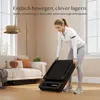 A woman is shown folding a compact treadmill in a living room setting. Anteprima dell’immagine prodotto