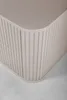 A close-up view of the corner of a beige bathroom cabinet with vertical ribbed detailing. Voir les images du produit