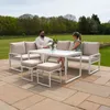 A couple sitting on an outdoor sofa set with a table and stools on a patio, with a garden and trees in the background. Produktbild-Vorschau