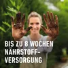 A woman with dirty hands in front of a green, leafy background. Náhľad obrázku produktu