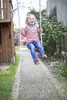 A young girl is swinging on a wooden swing set in a backyard. Produktbild-Vorschau